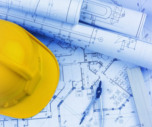 Blueprints construction and a yellow hardhat with a compass Blueprints construction and a yellow hardhat with a compass