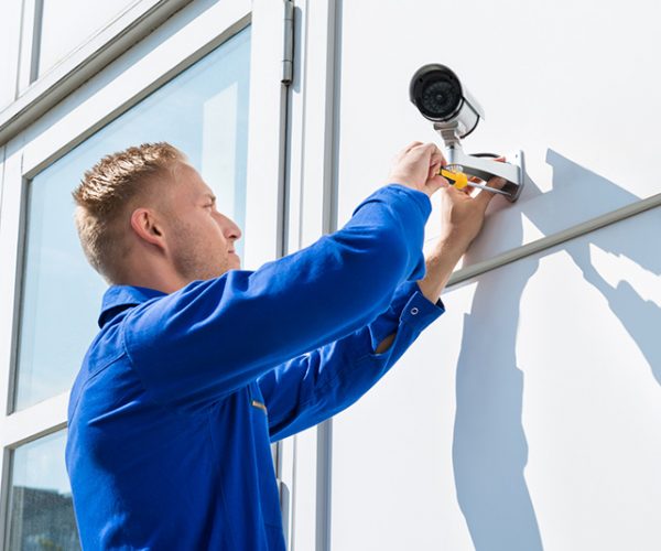 security1 man installing security camera on side of building